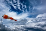 an orange and white flag on a pole under a cloudy sky