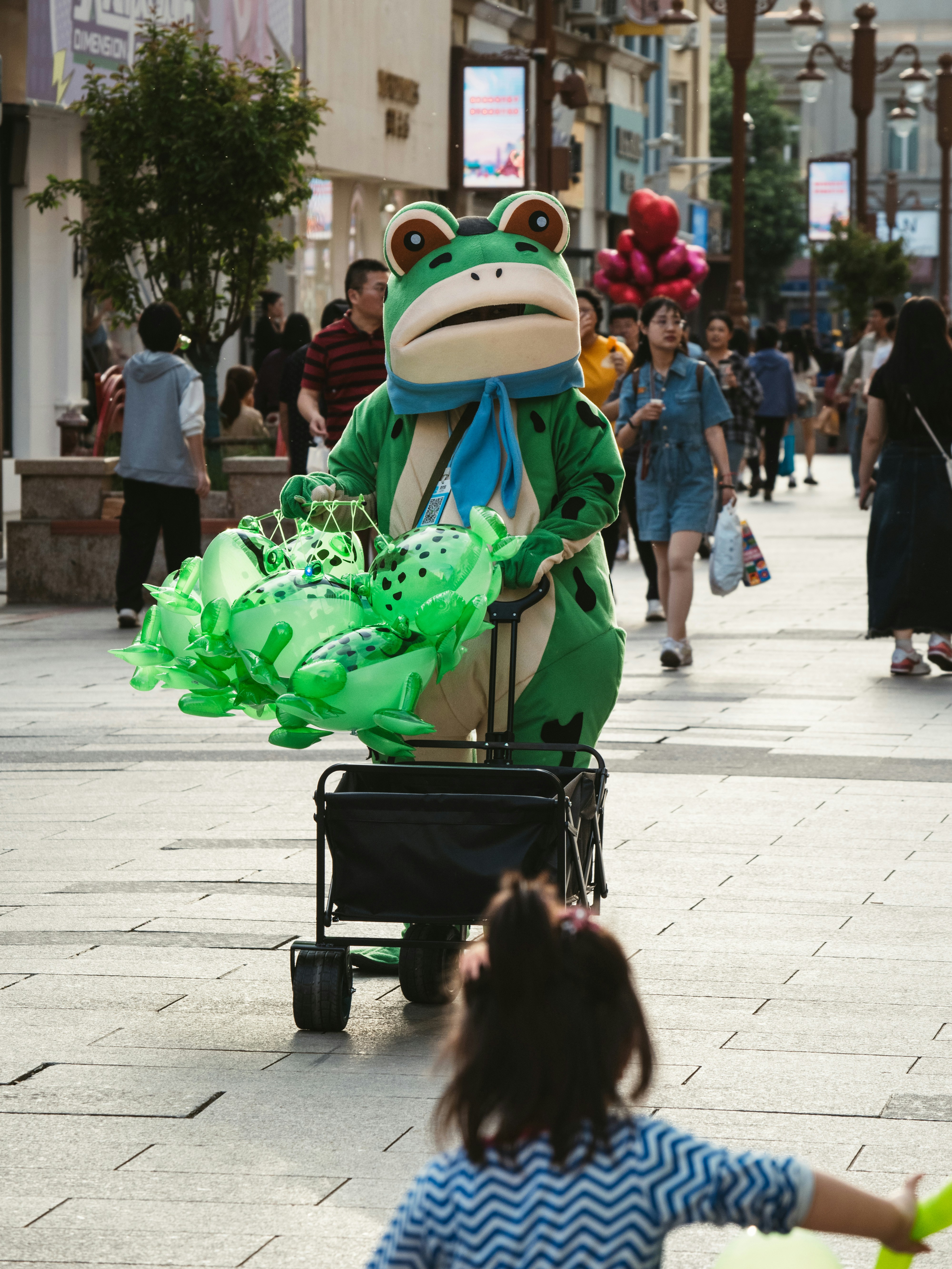 a little girl pushing a cart with a frog on it