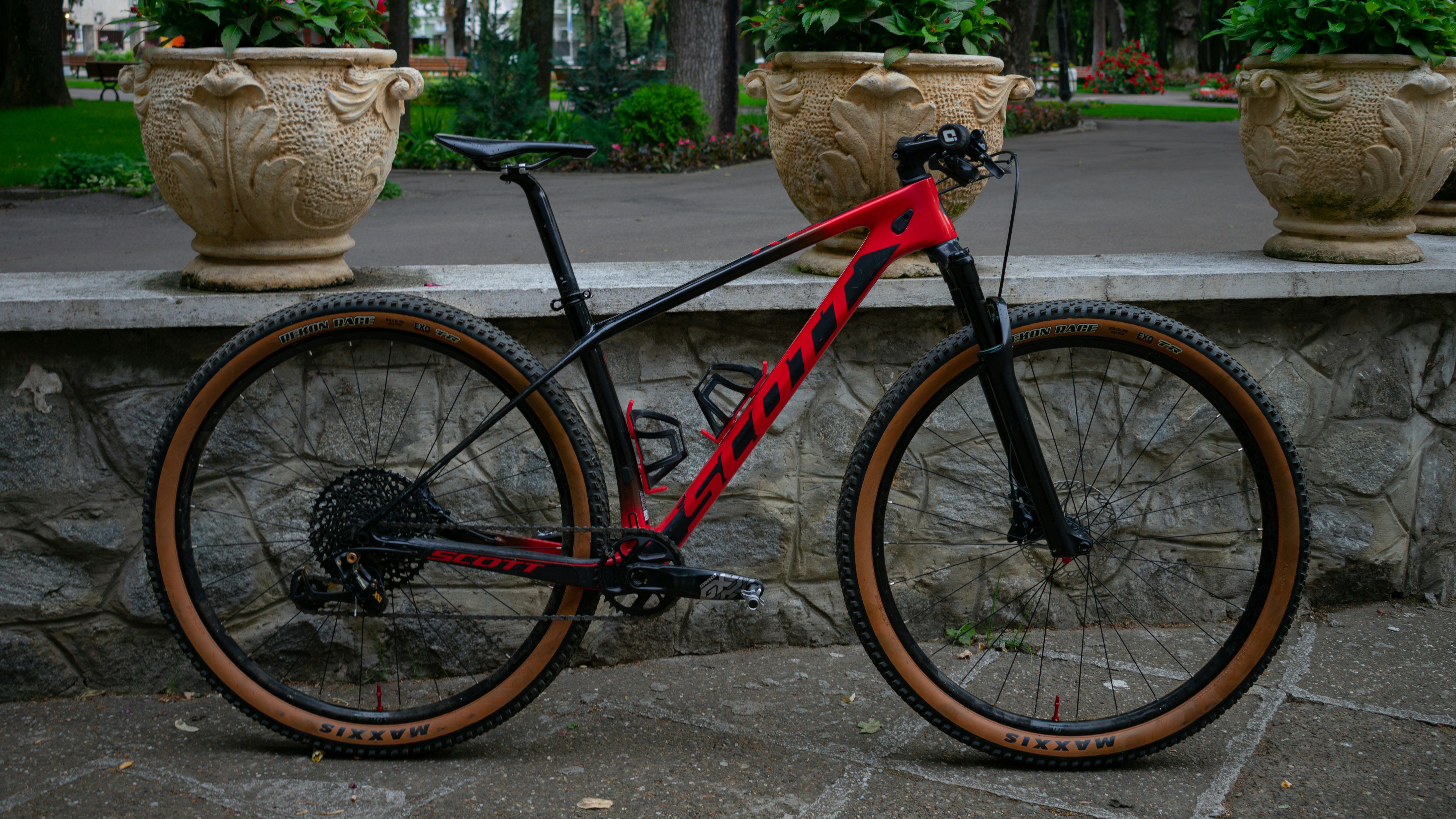 a red and black bike parked next to a stone wall