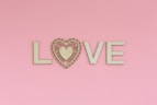 the word love spelled with a heart on a pink background
