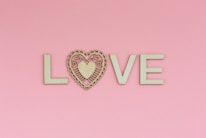 the word love spelled with a heart on a pink background
