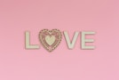 the word love spelled with a heart on a pink background