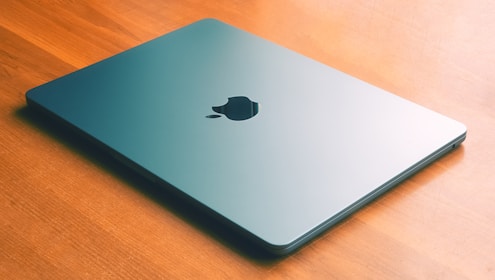 an apple laptop sitting on a wooden table