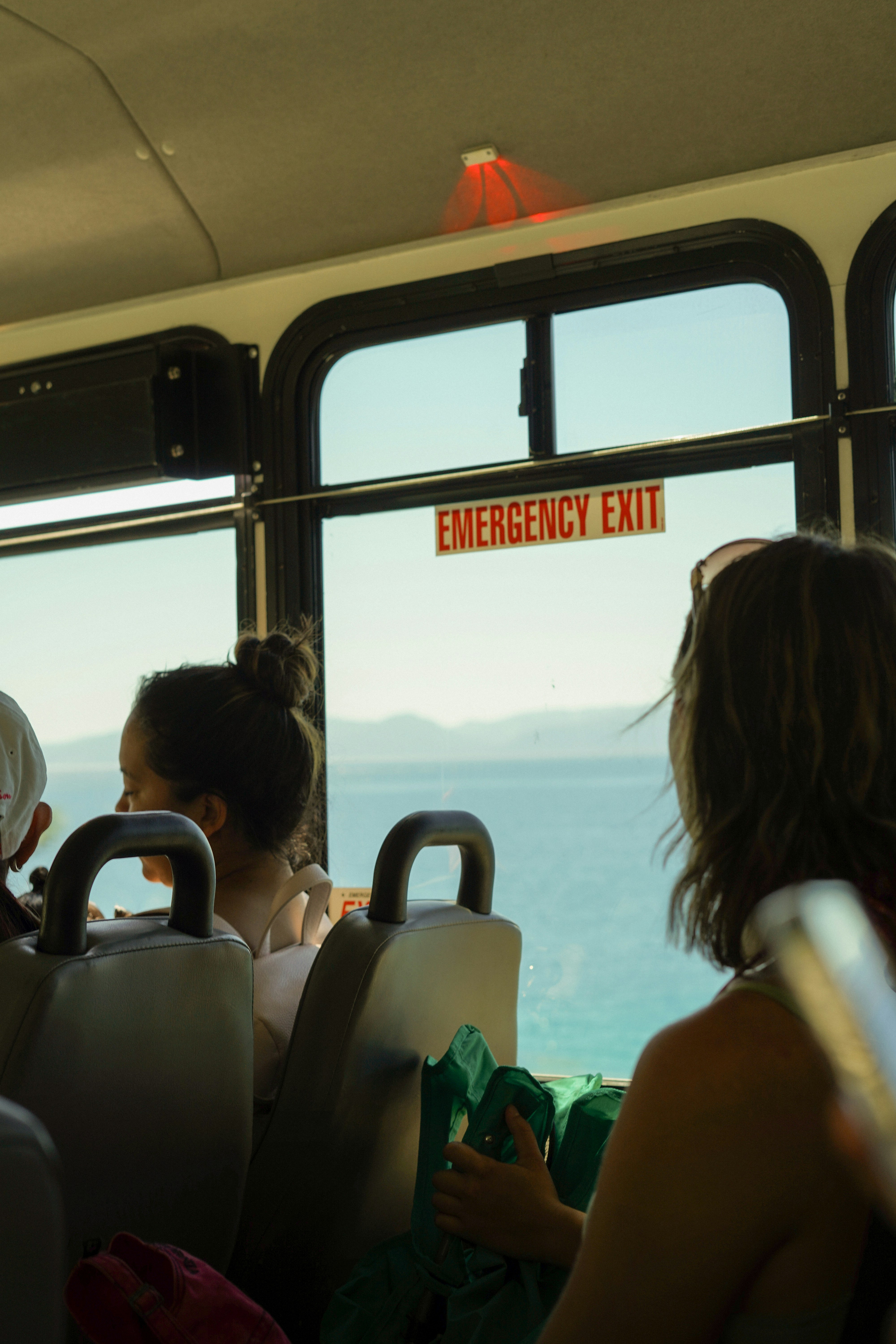 a group of people sitting on a bus next to the ocean