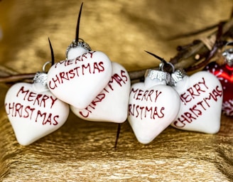three white heart ornaments with merry christmas written on them
