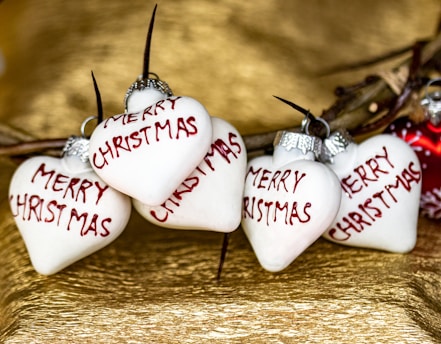 three white heart ornaments with merry christmas written on them