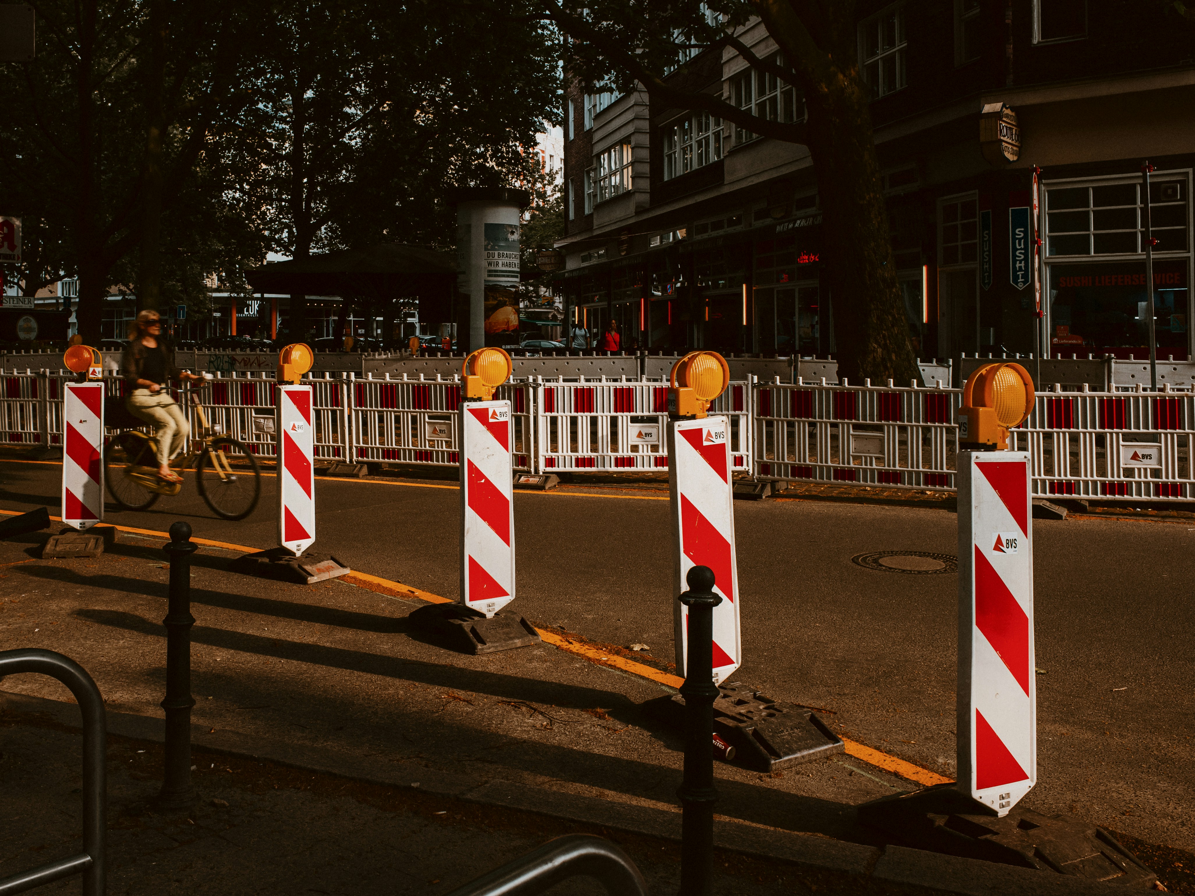 a street that has some red and white striped barriers, 