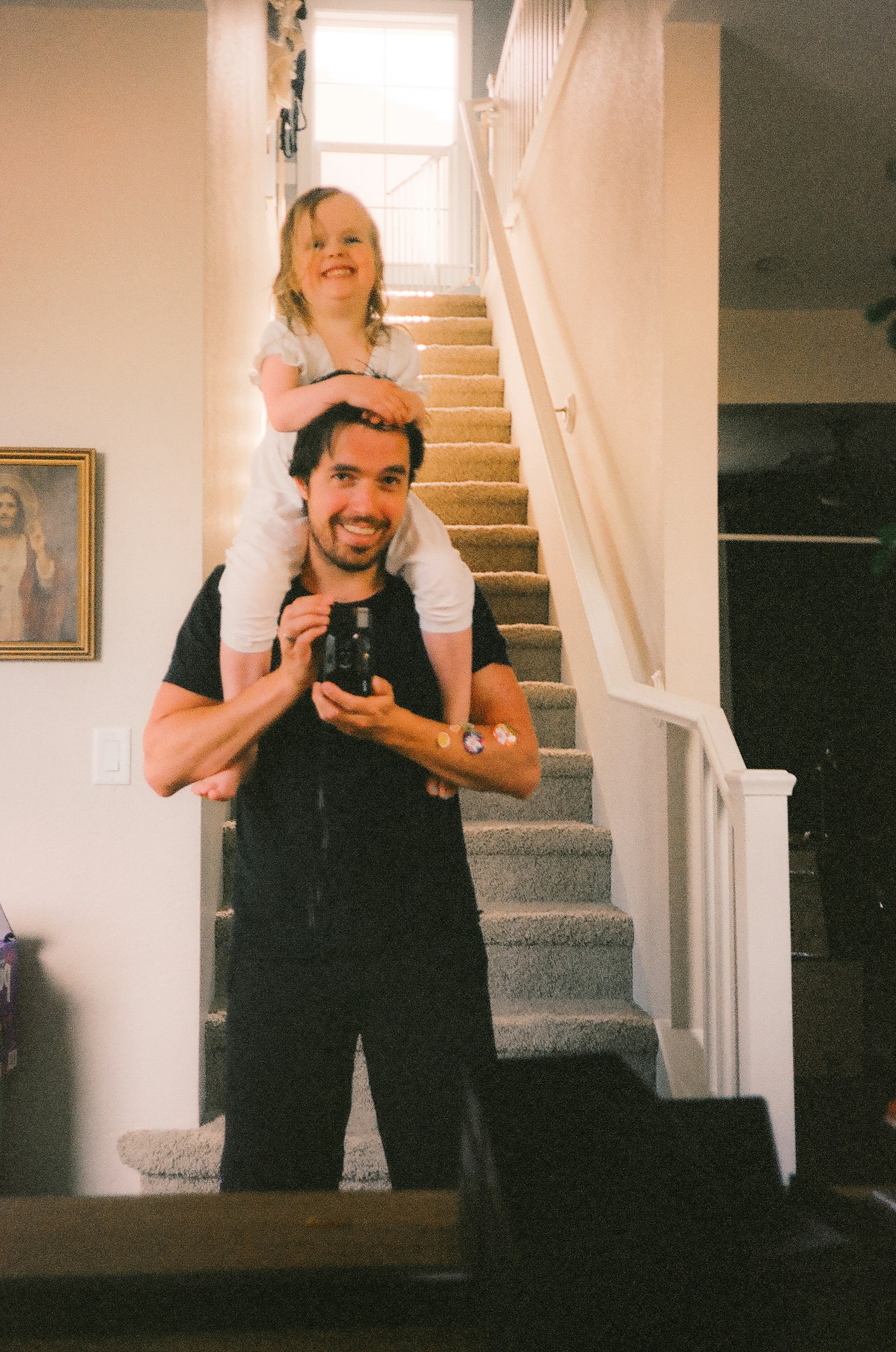 a man holding a little girl on his shoulders