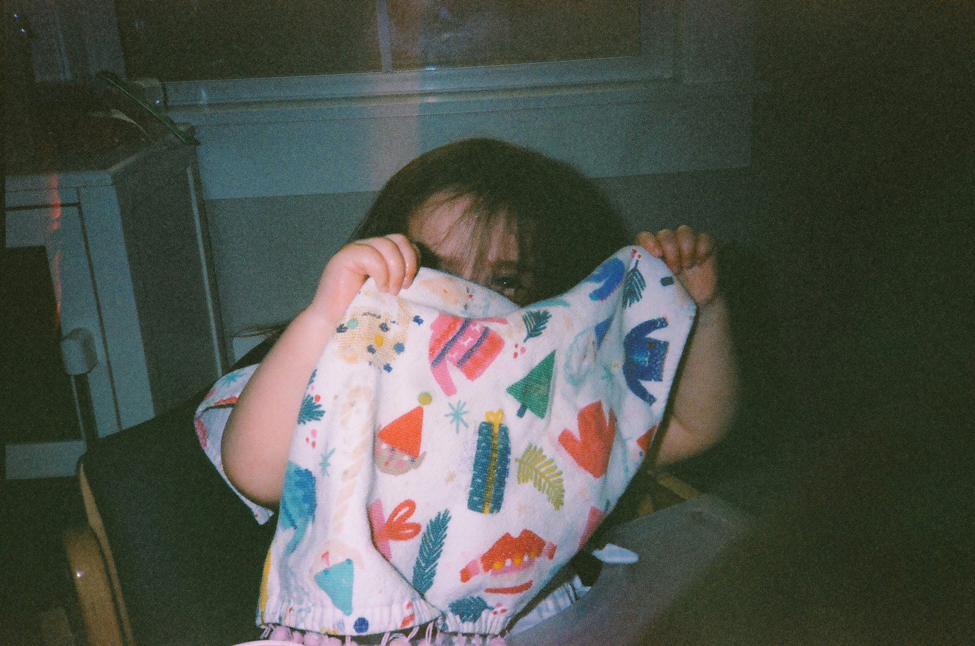 a little girl holding a blanket over her face