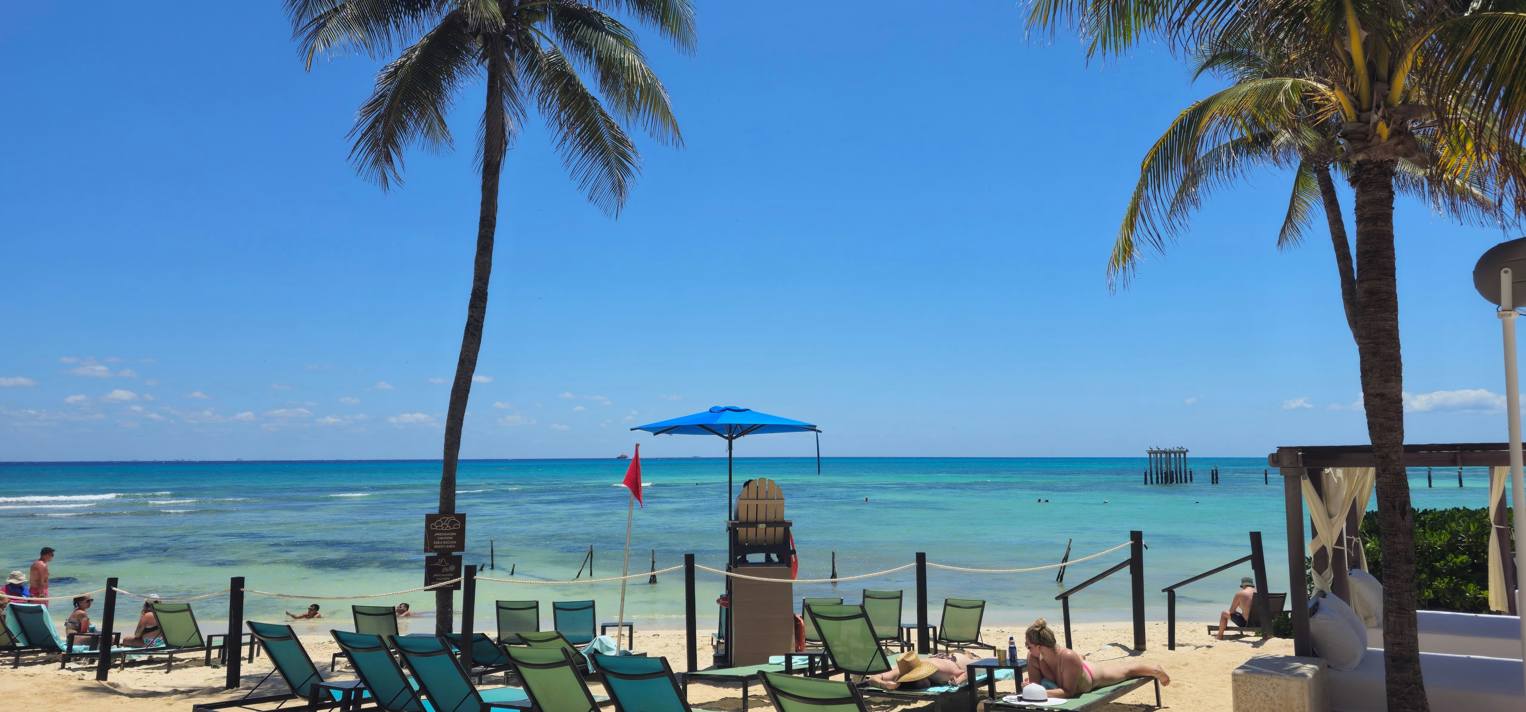 a beach with a bunch of lawn chairs and a blue umbrella