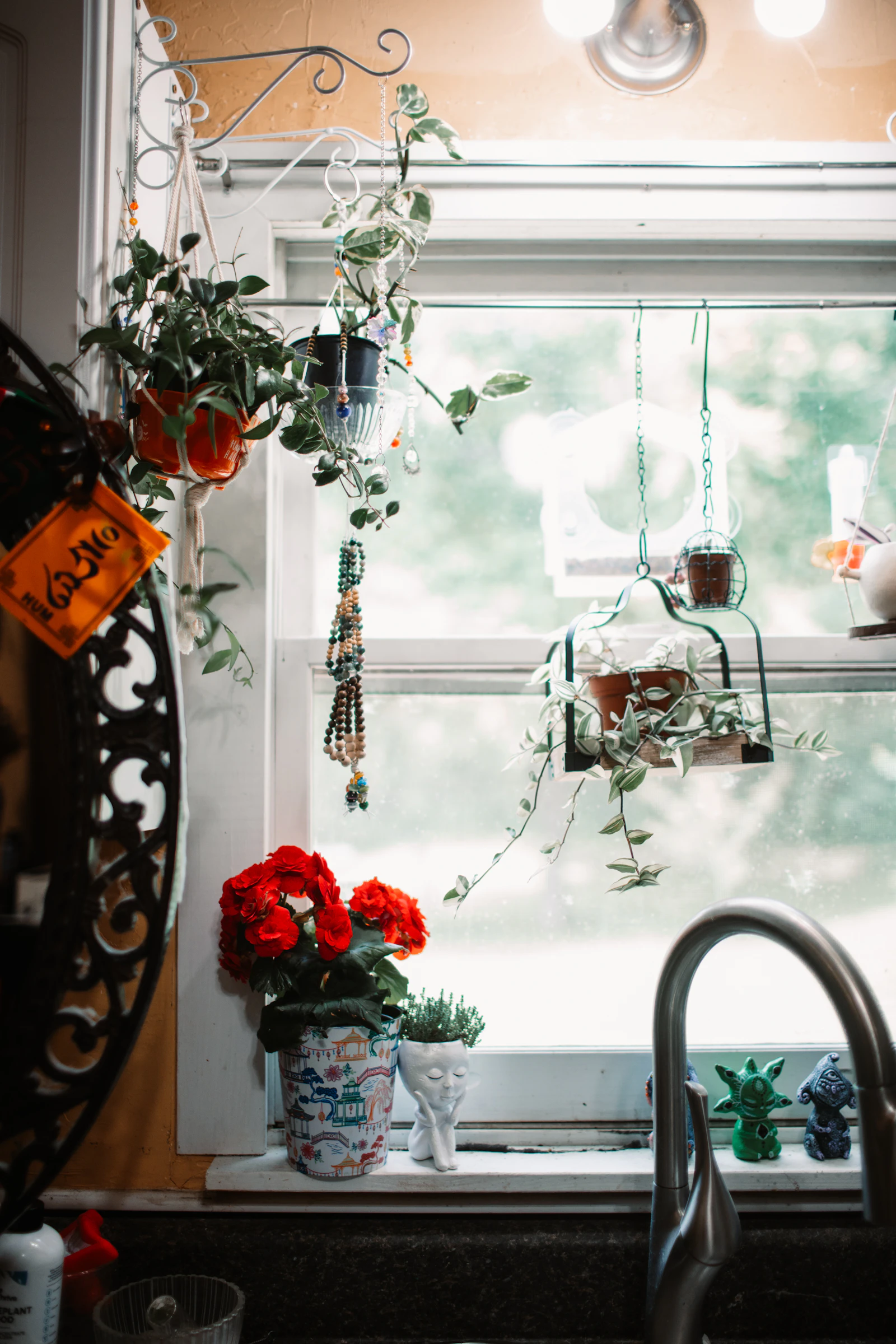 A kitchen window with a sink and a windowsill filled with potted herbs and plants