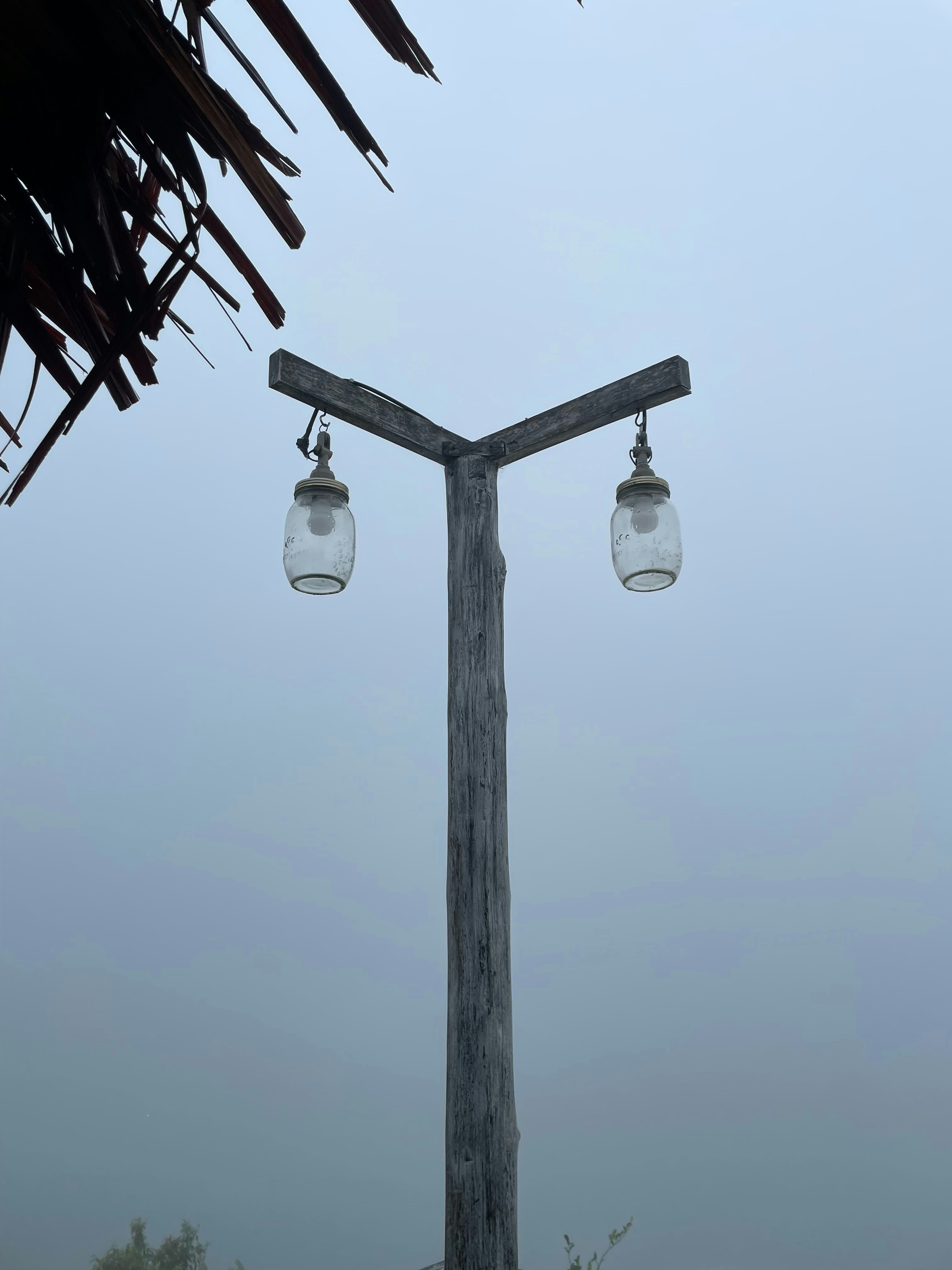 un poste de madera del que cuelgan dos frascos de vidrio