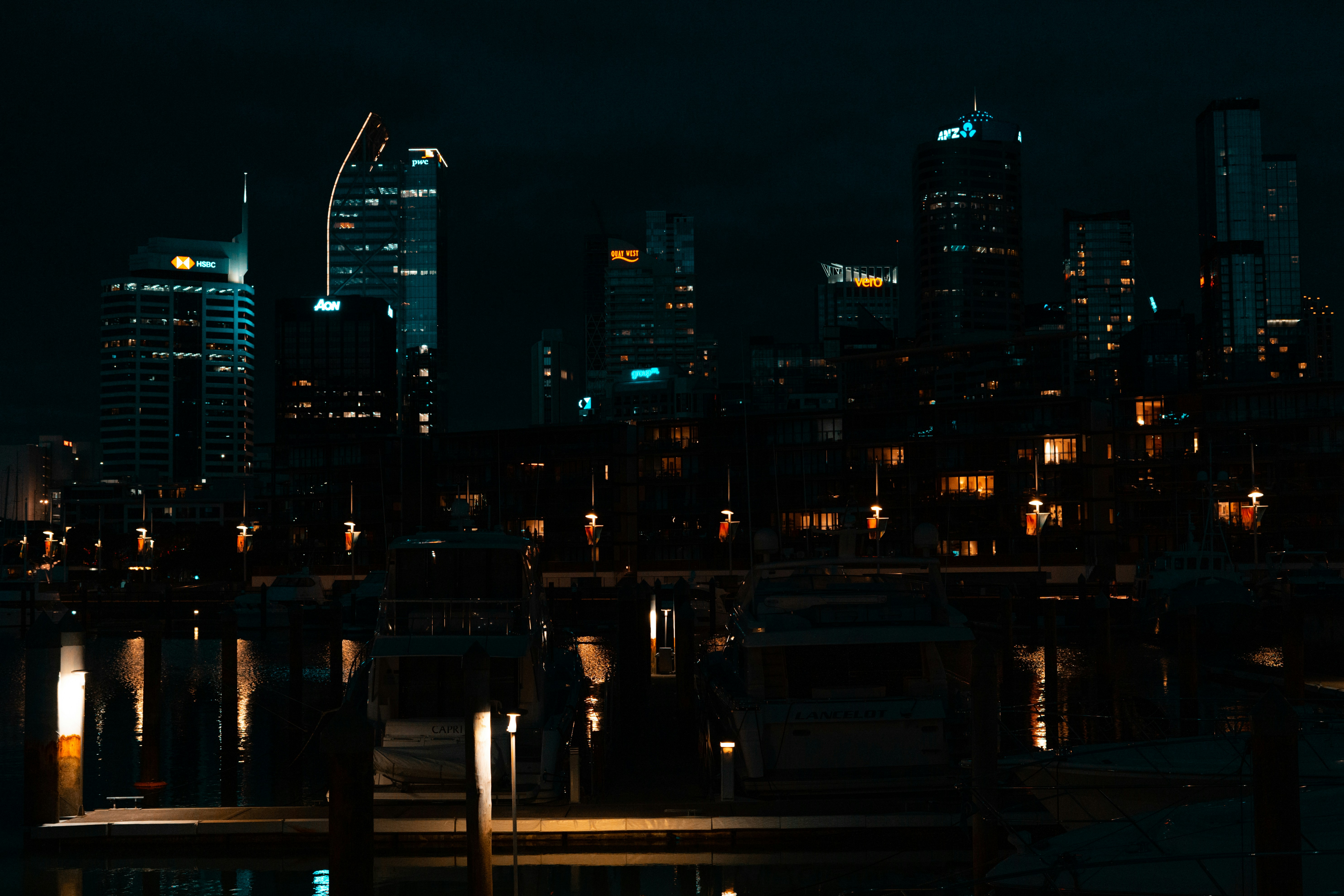 a night view of a city skyline with boats in the water