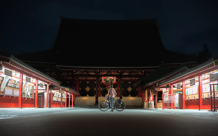 A cyclist passing Senso-ji at night