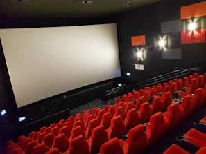 an empty theater with red seats and a projector screen
