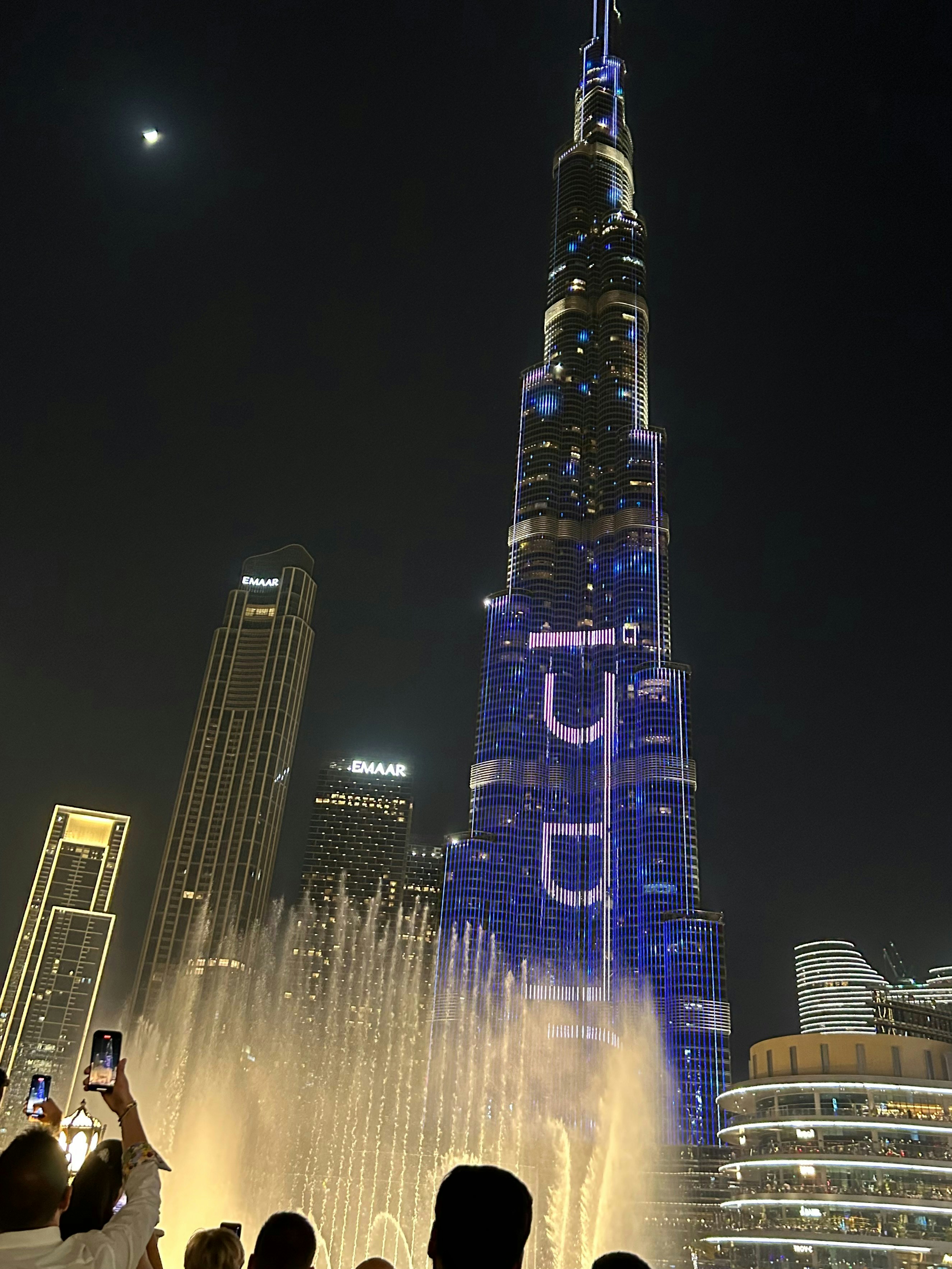 Predstava Dubai Fountain ponoči z osvetljenim Burj Khalifa v ozadju