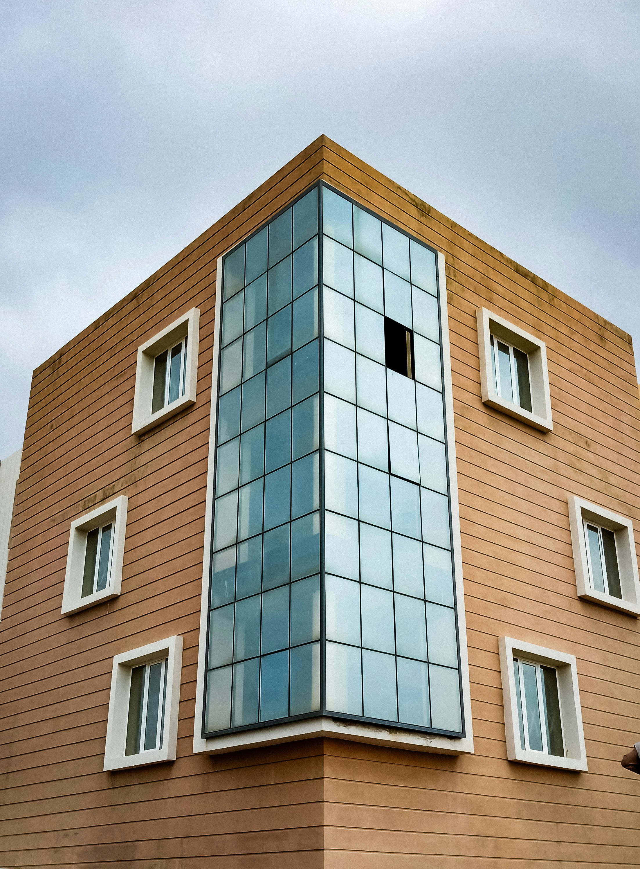 A tall brown building with windows and a sky background photo – Free ...