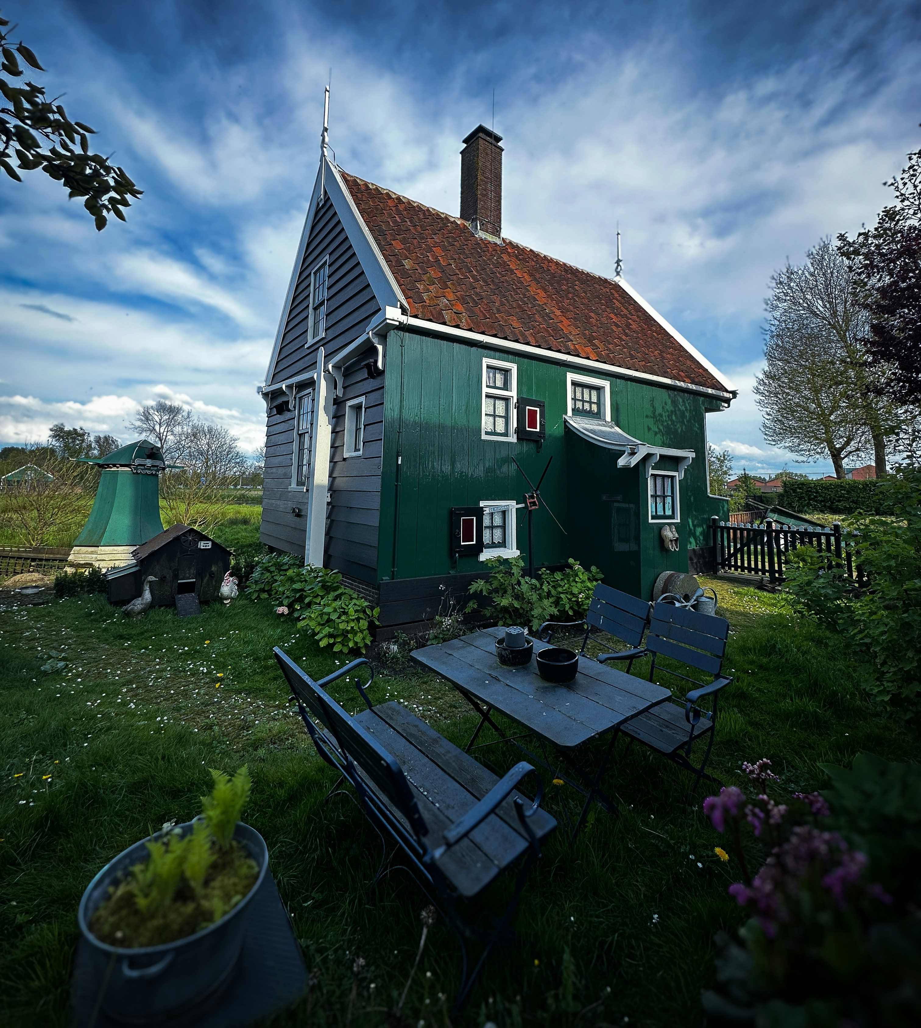 a green house with a table and chairs in front of it