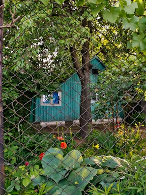 a green house behind a chain link fence