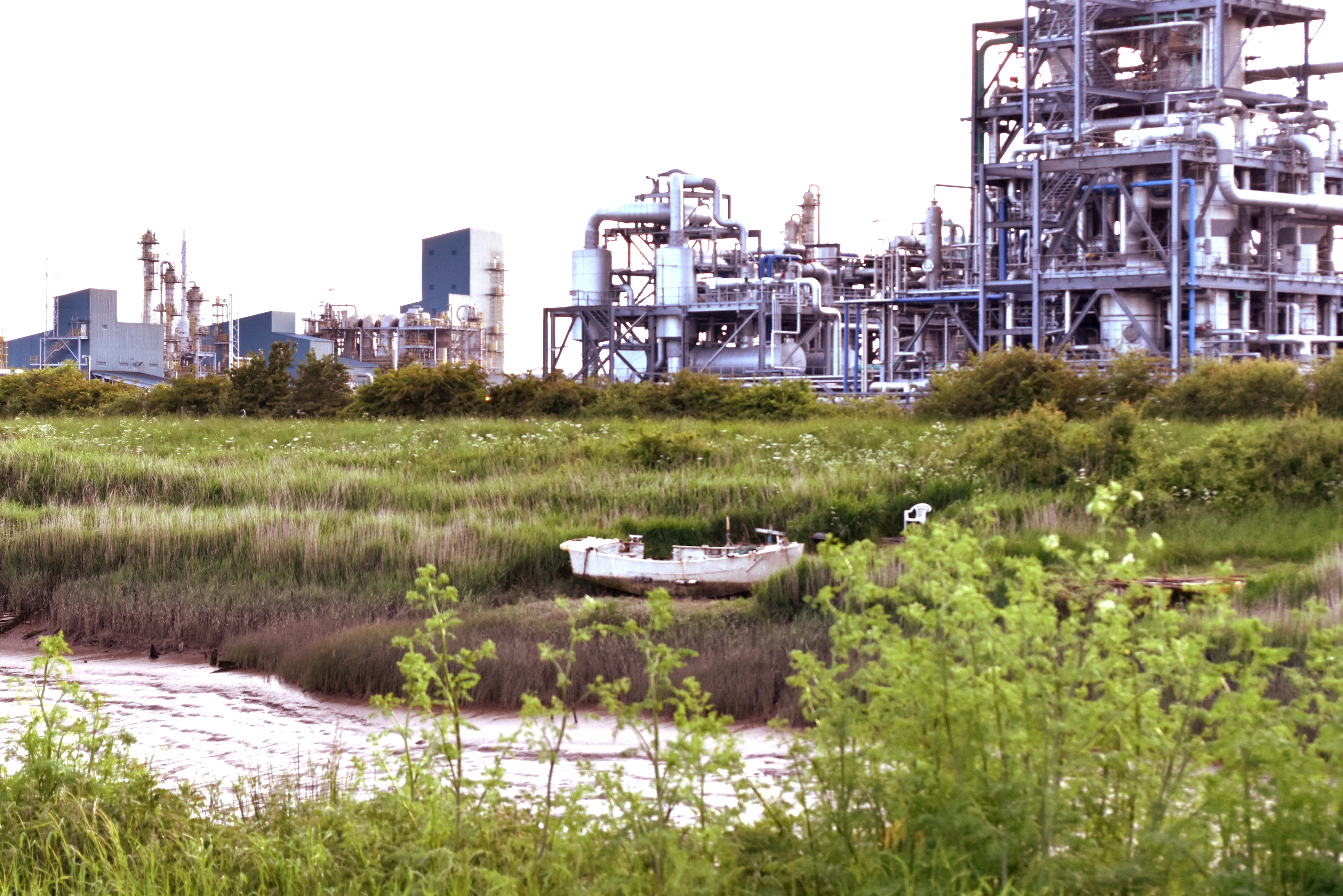 a boat sitting in the grass in front of a factory