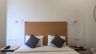 a bed with two pillows and a night stand