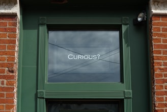 a green door with a sign that says curious