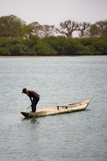a man standing on a boat in the middle of a lake