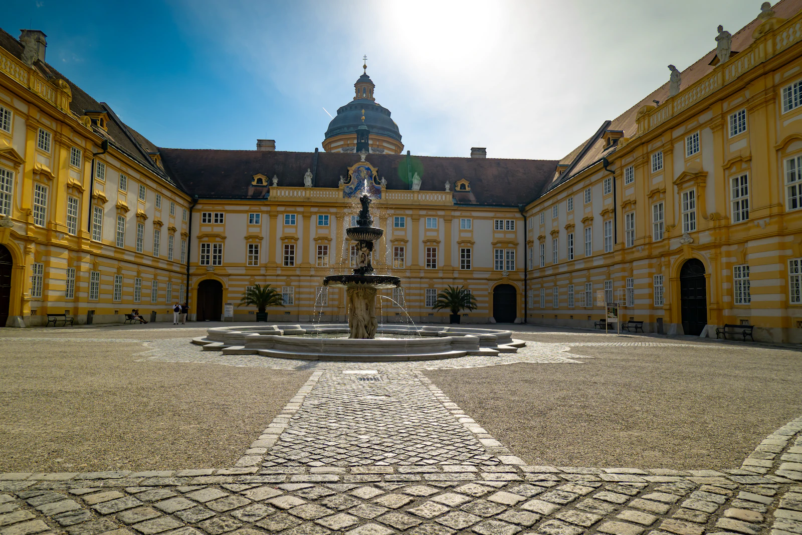 Travel photograph: Melk Abbey's broad courtyard framed by ochre-and-white Baroque façades.