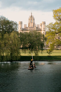 a man on a small boat in a lake in front of a castle