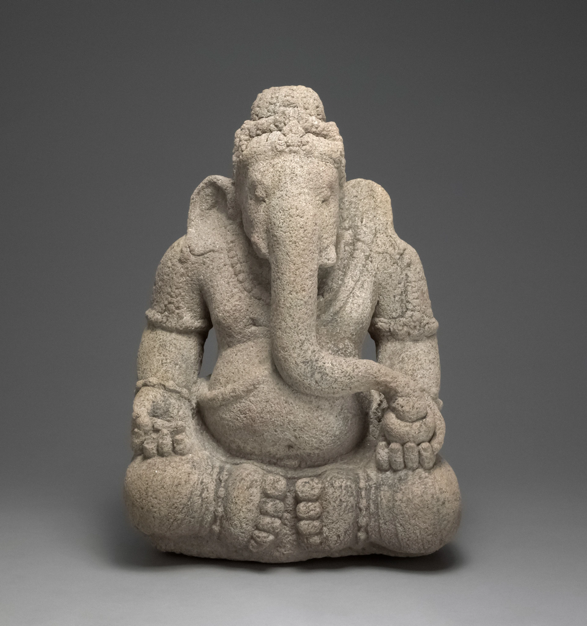 Stone sculpture of ganesha sitting cross-legged
