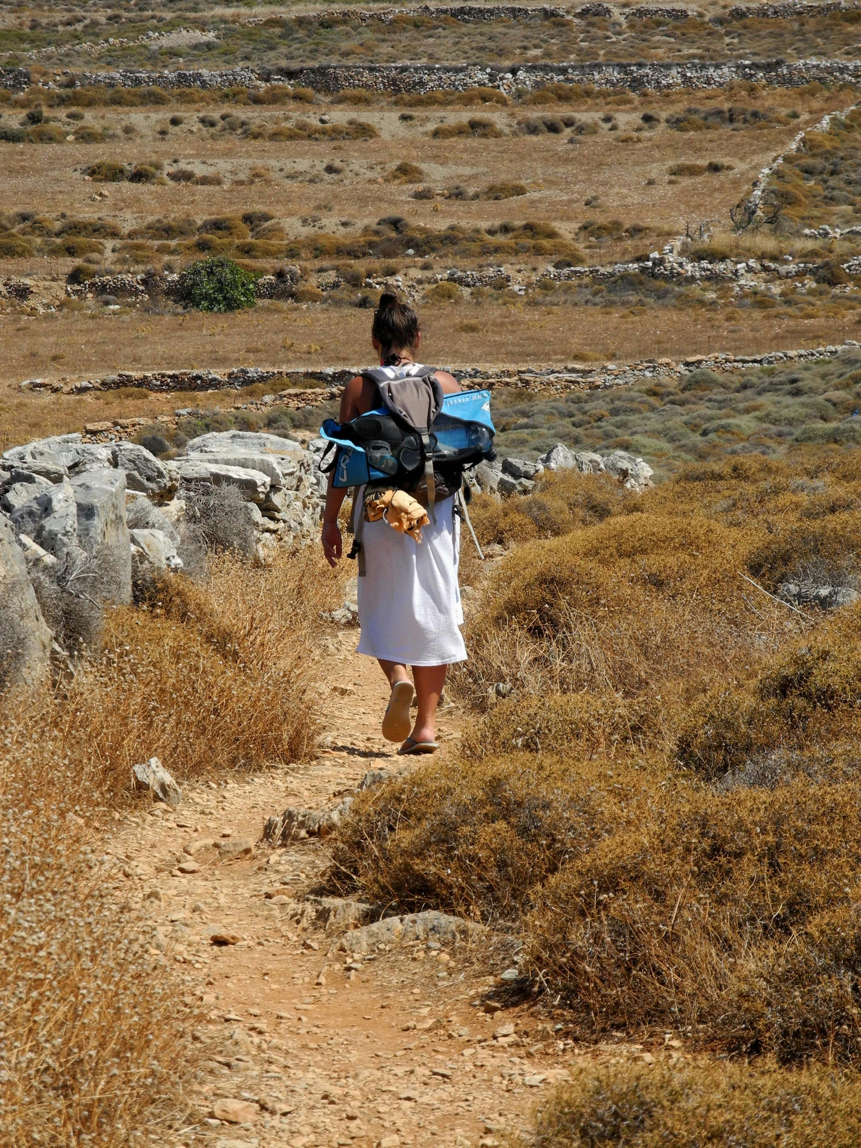 a woman walking down a dirt path with a backpack