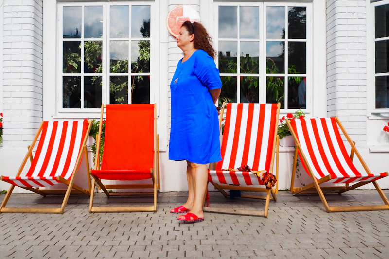 Sugar Mommy de pie frente a una silla de jardín a rayas.