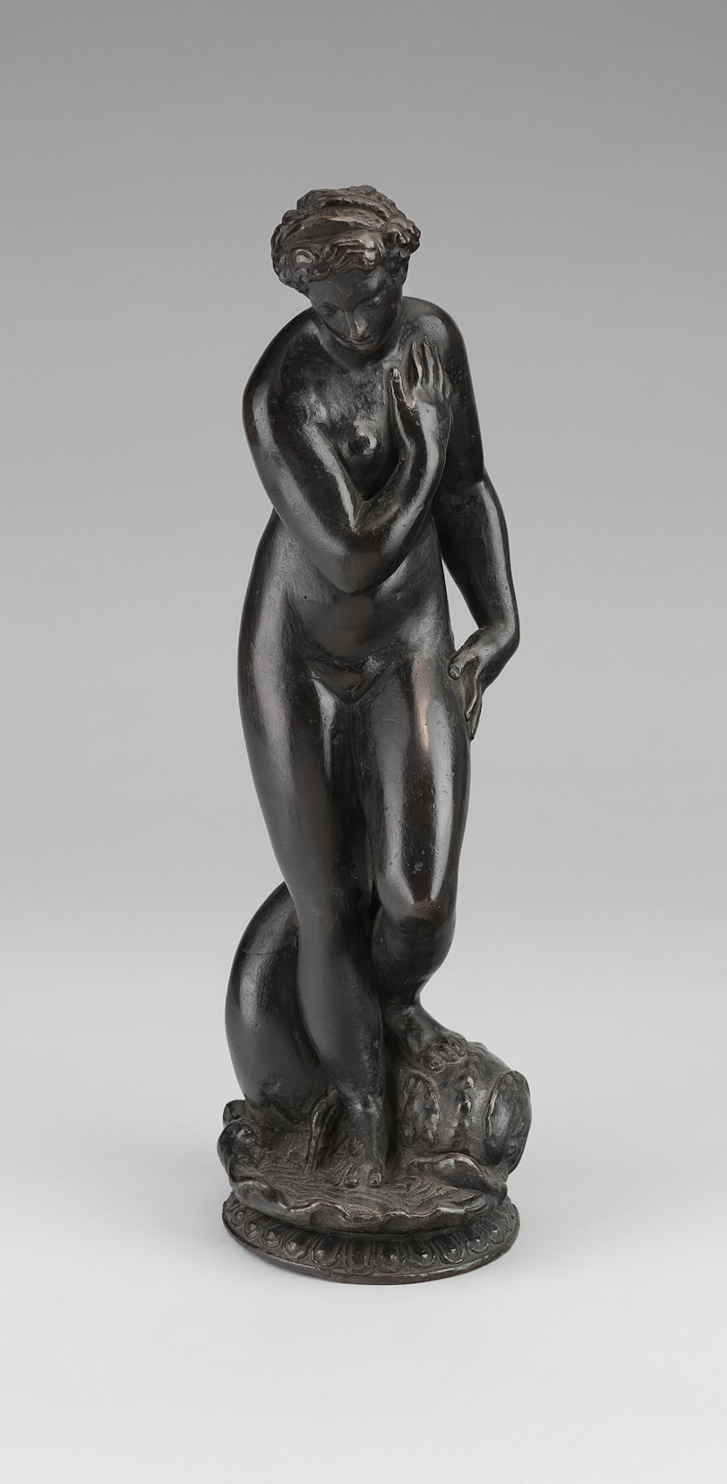 Bronze sculpture of a nude woman with dolphin base