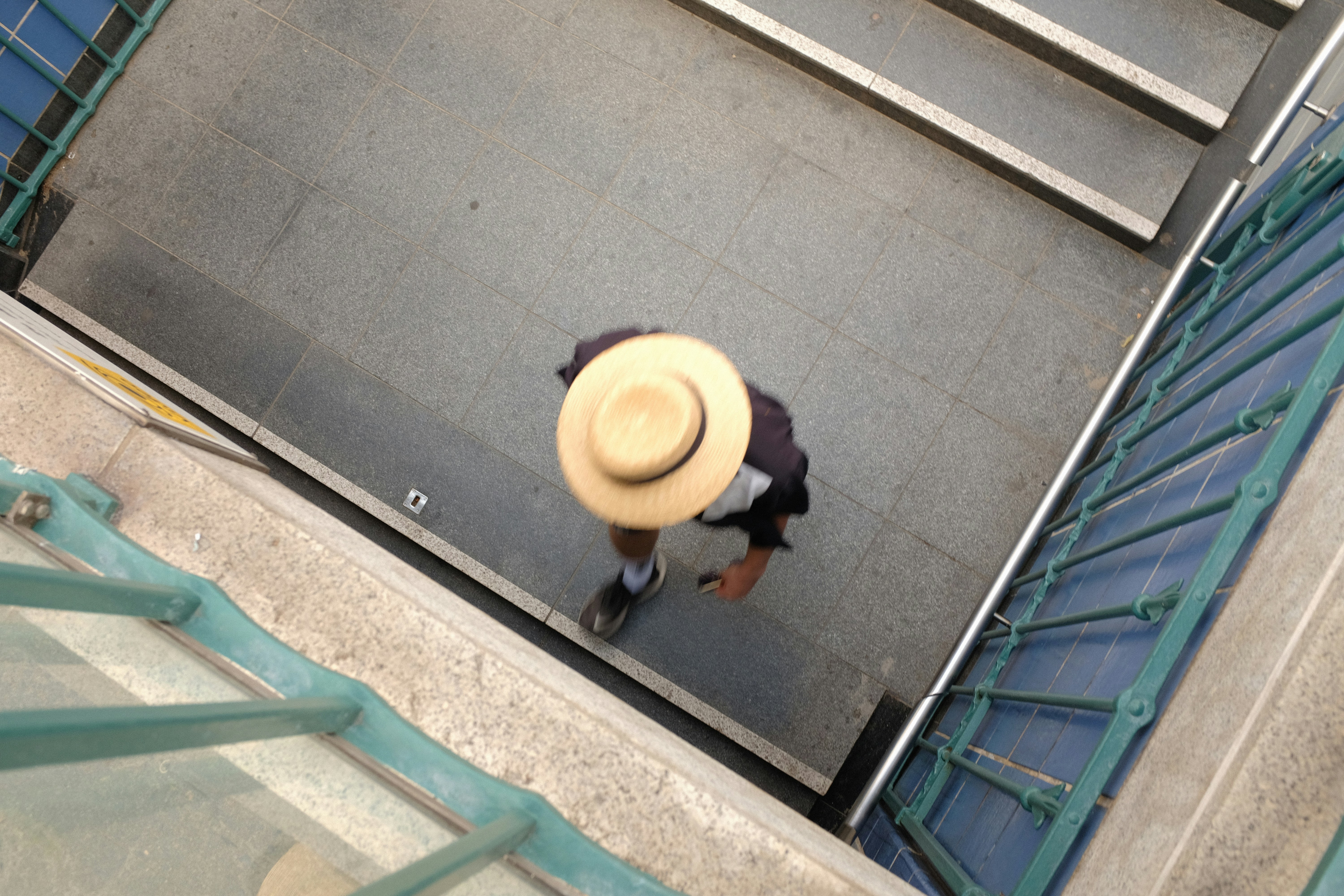 a person with a hat walking down a flight of stairs