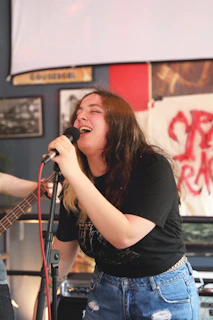 a woman singing into a microphone while holding a guitar