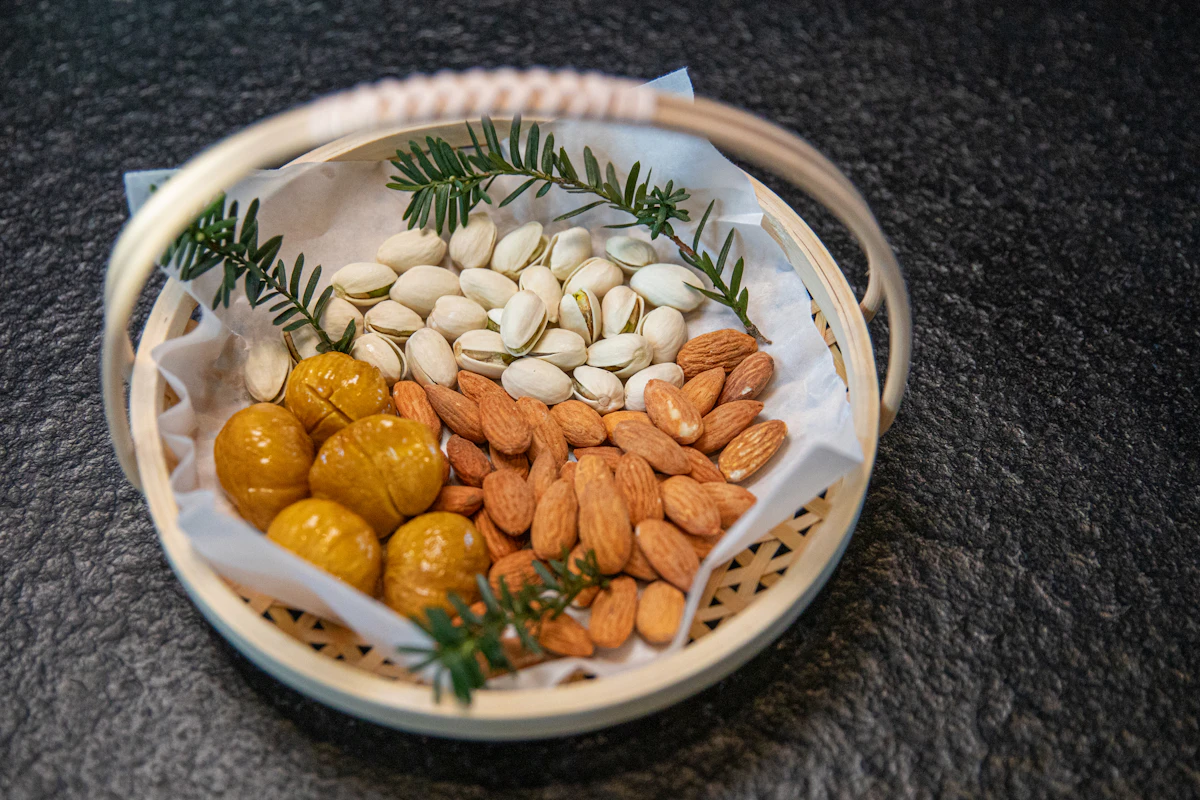 An open woven basket lined with paper, holding pistachios, almonds, and dried fruit