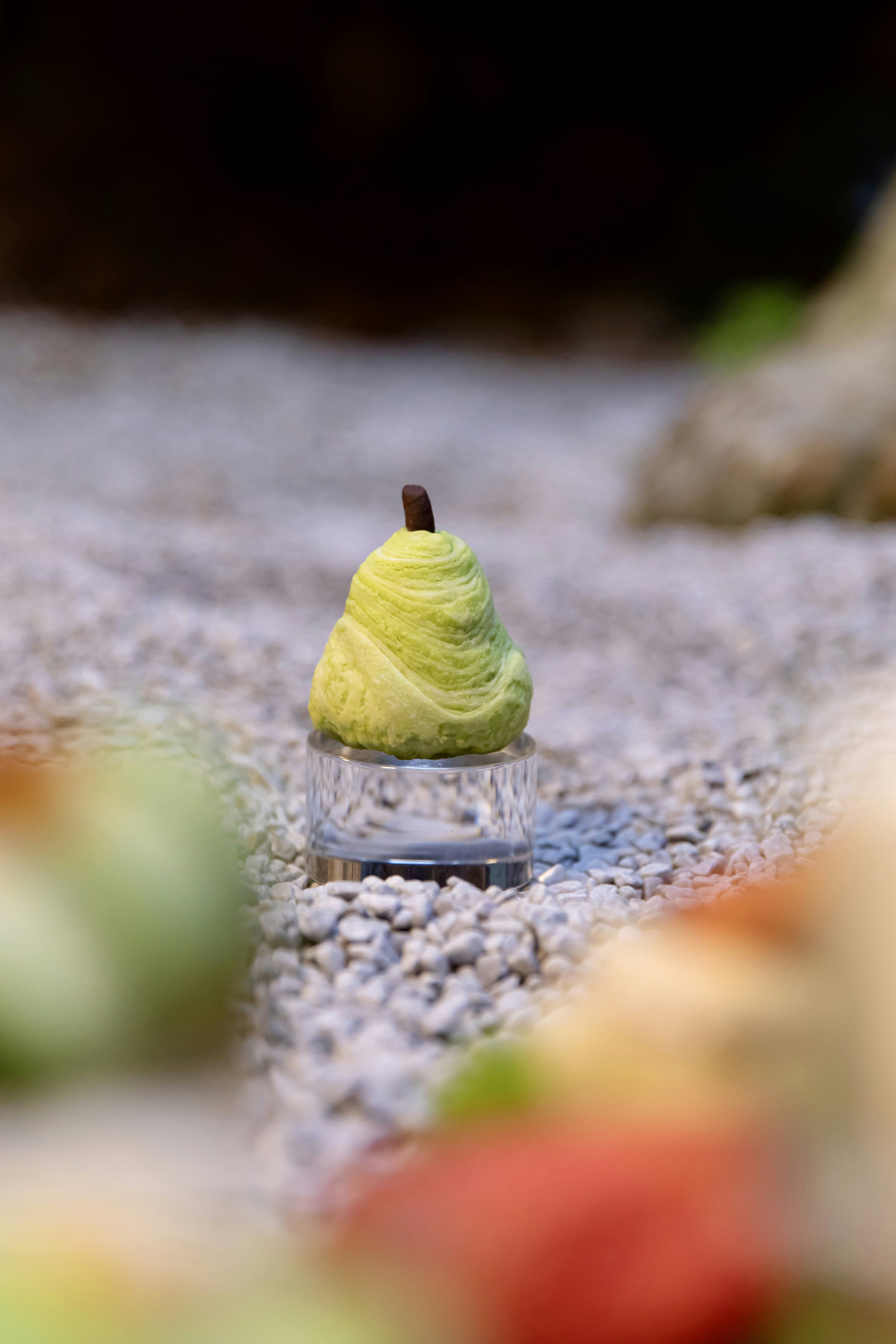 a green apple sitting on top of a rock covered ground