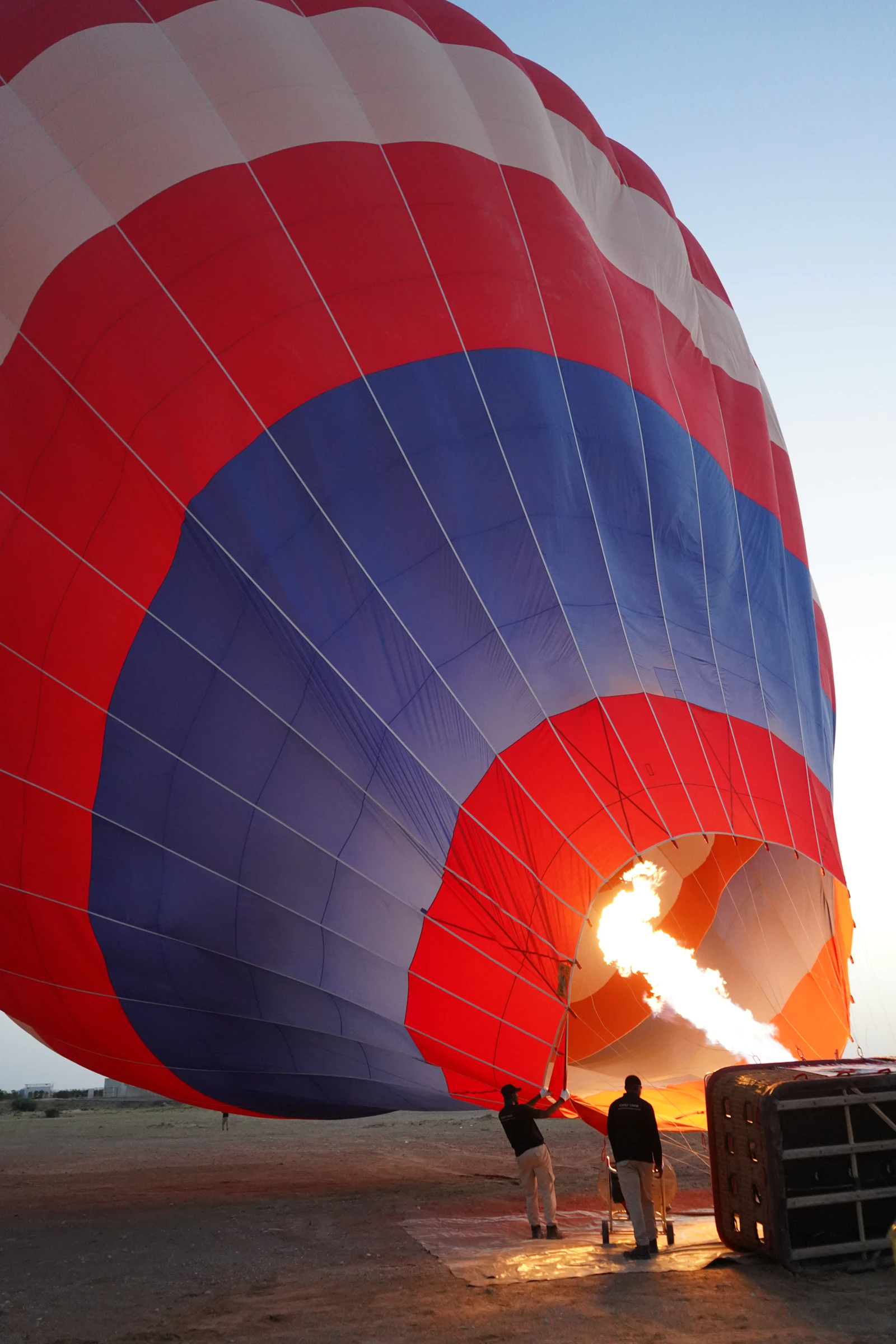 Crew firing the burner to inflate a hot air balloon at dawn in the Dubai desert