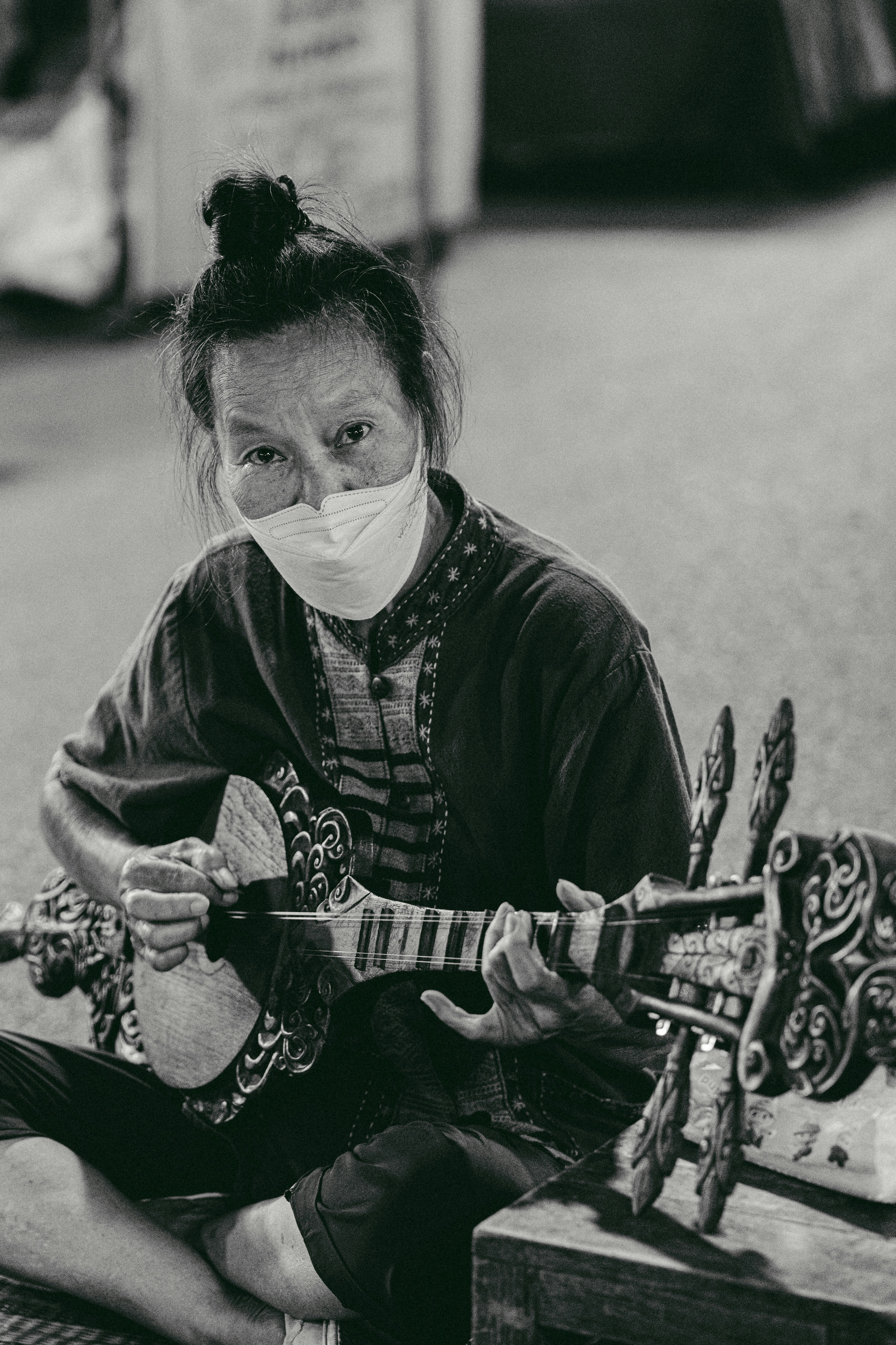 a woman sitting on the ground while playing a guitar