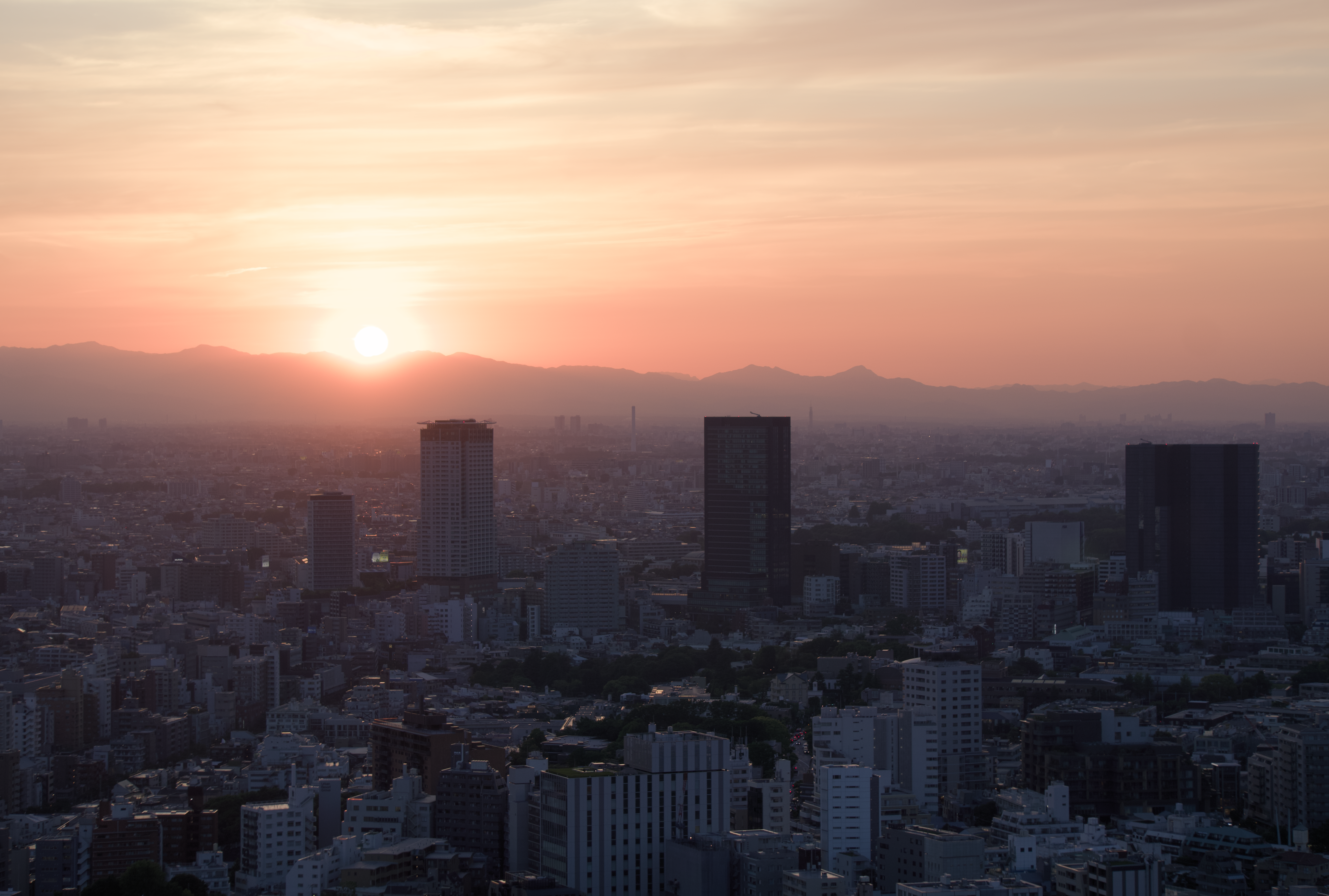 the sun is setting over a city with tall buildings, 