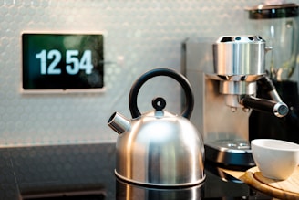 a tea kettle sitting on top of a counter next to a cup