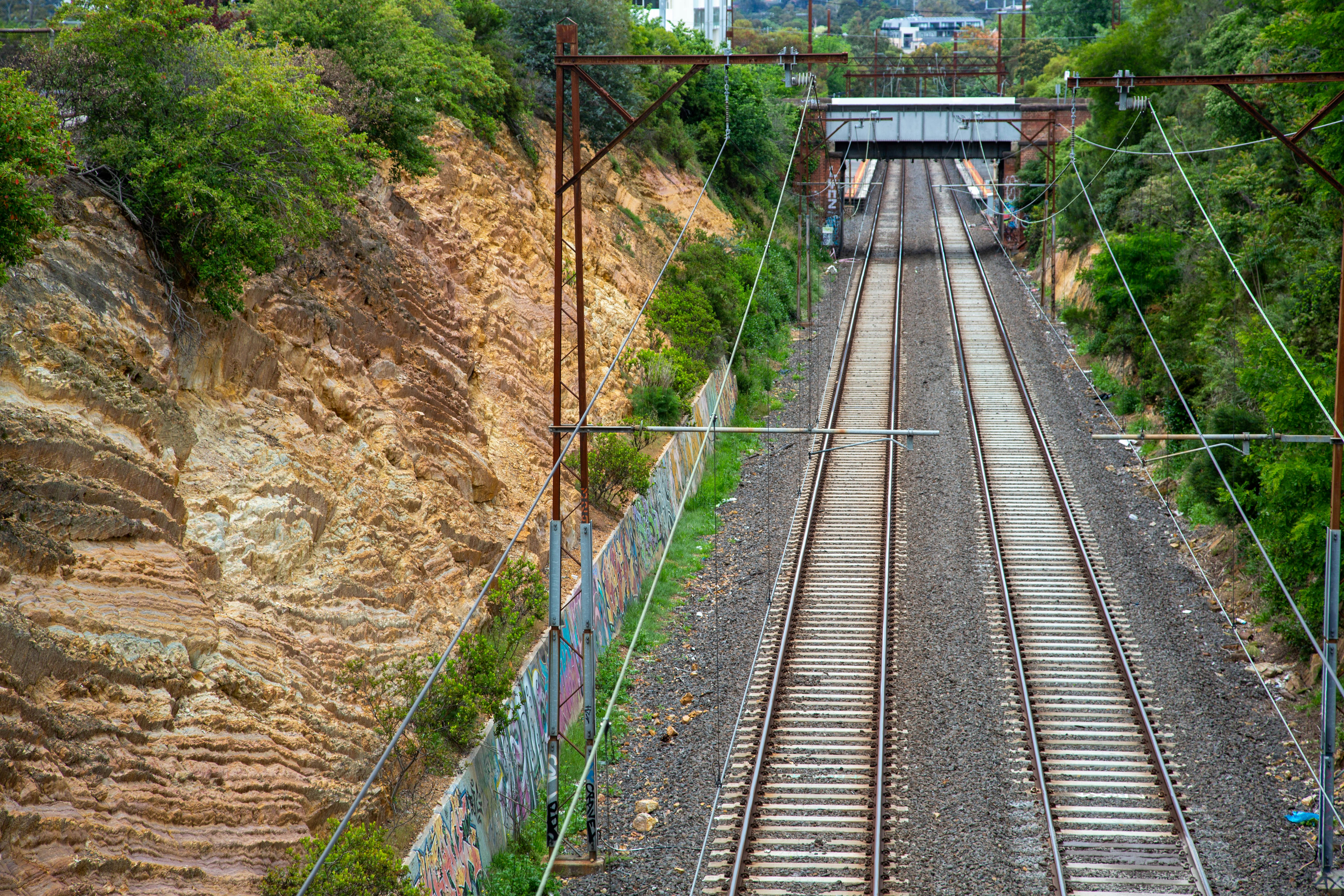 a train traveling down tracks next to a lush green hillside