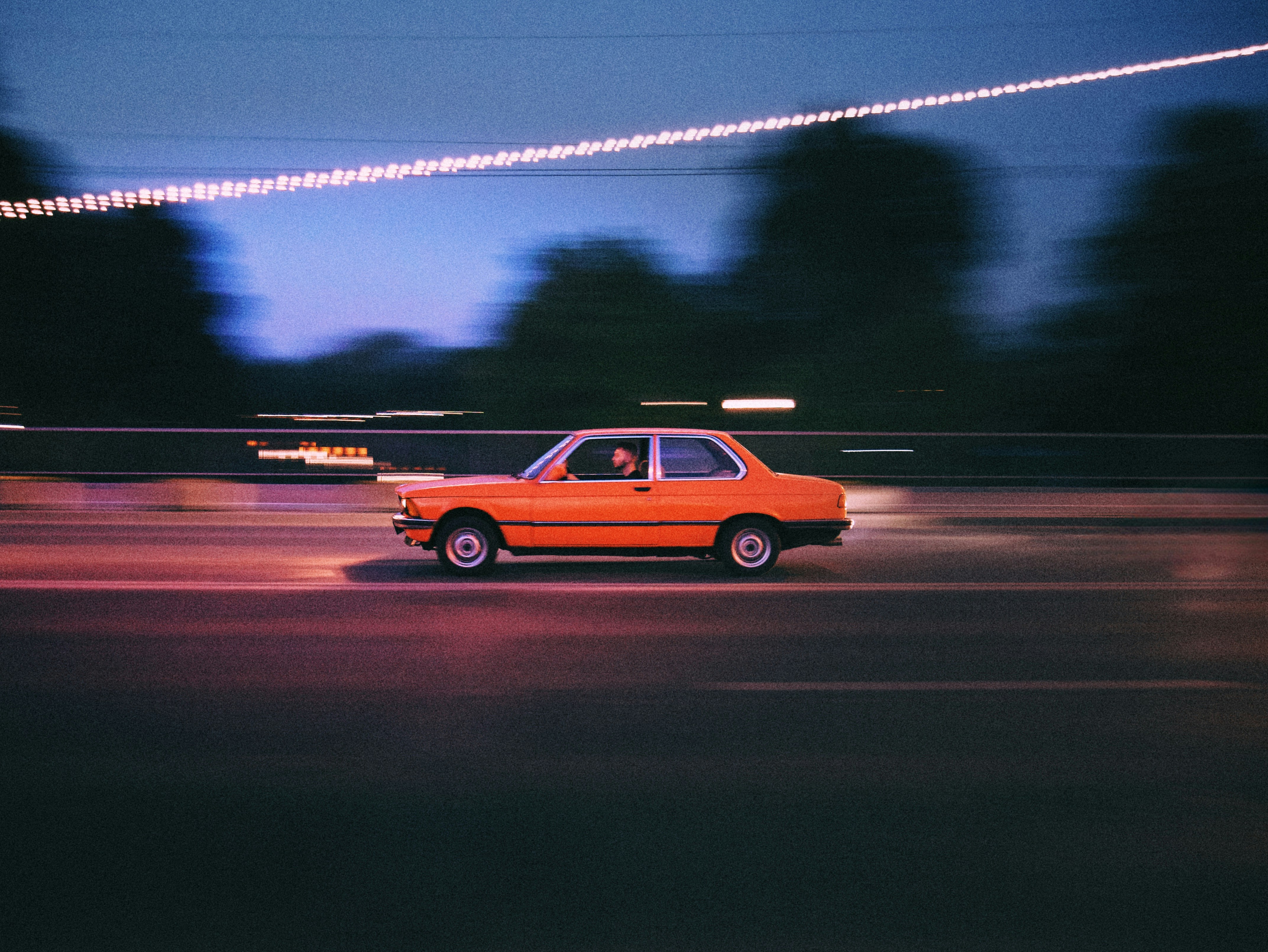 une voiture orange roulant dans une rue la nuit