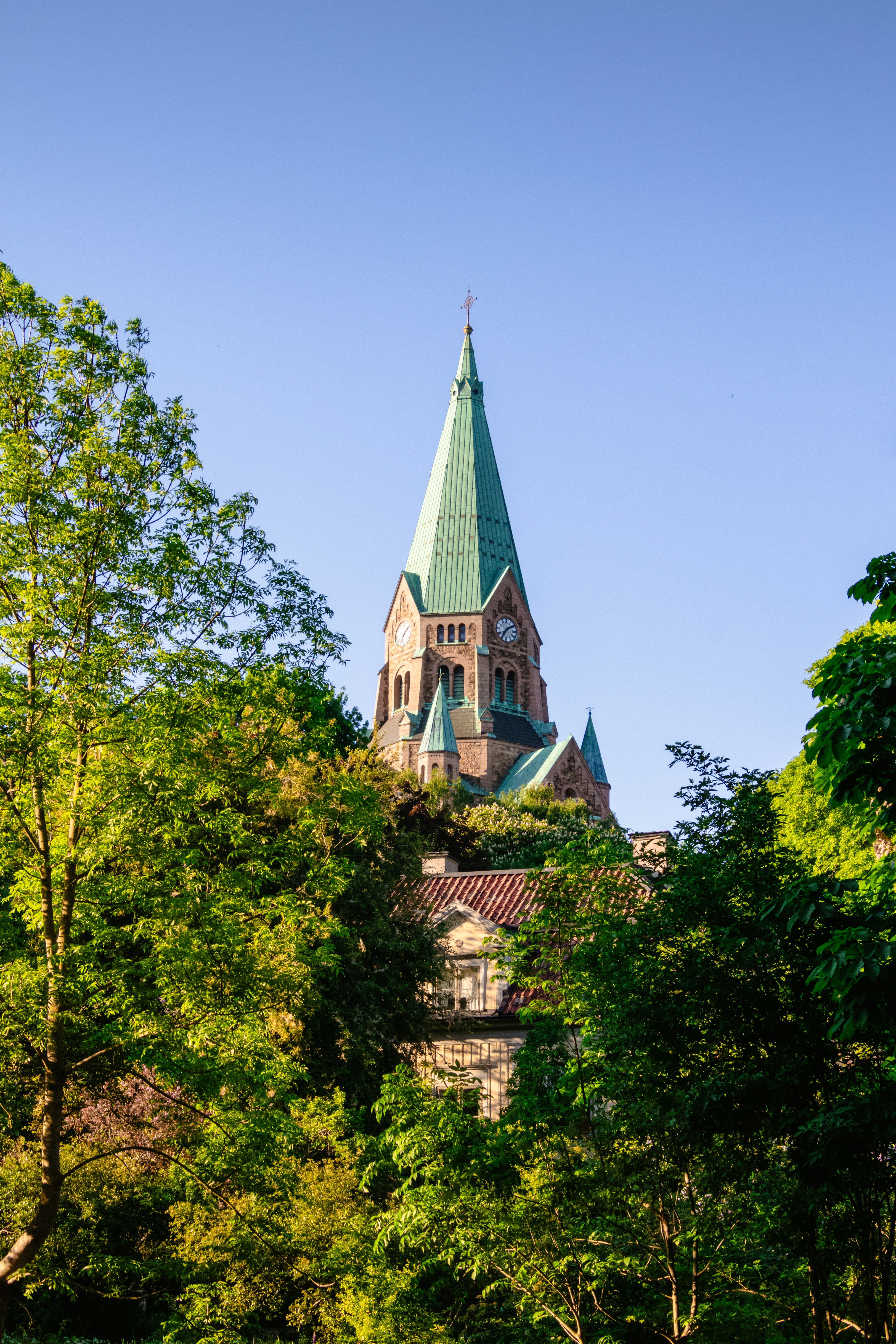 ein hohes Gebäude mit einem von Bäumen umgebenen Kirchturm