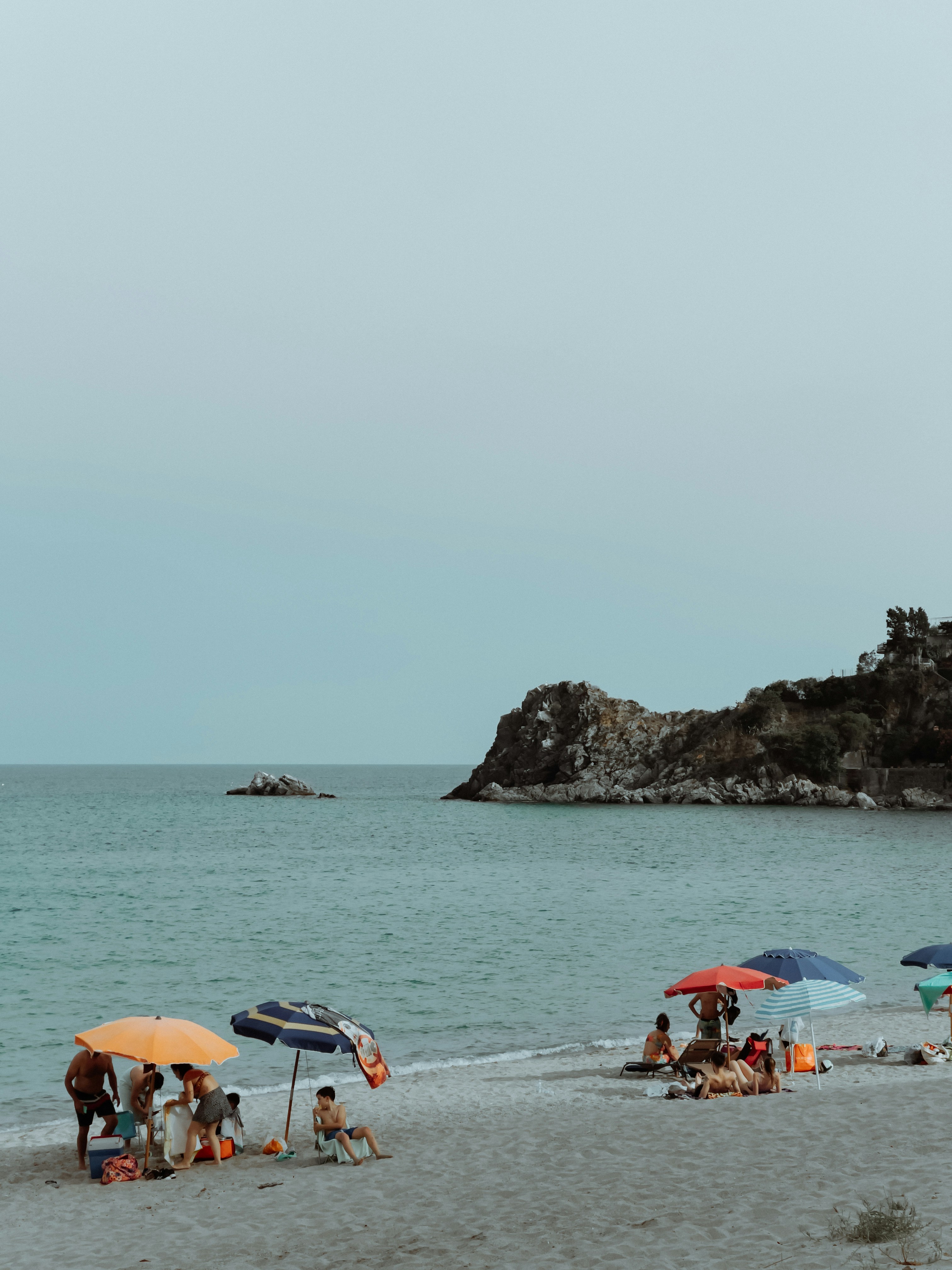 a group of people sitting on top of a beach under umbrellas
