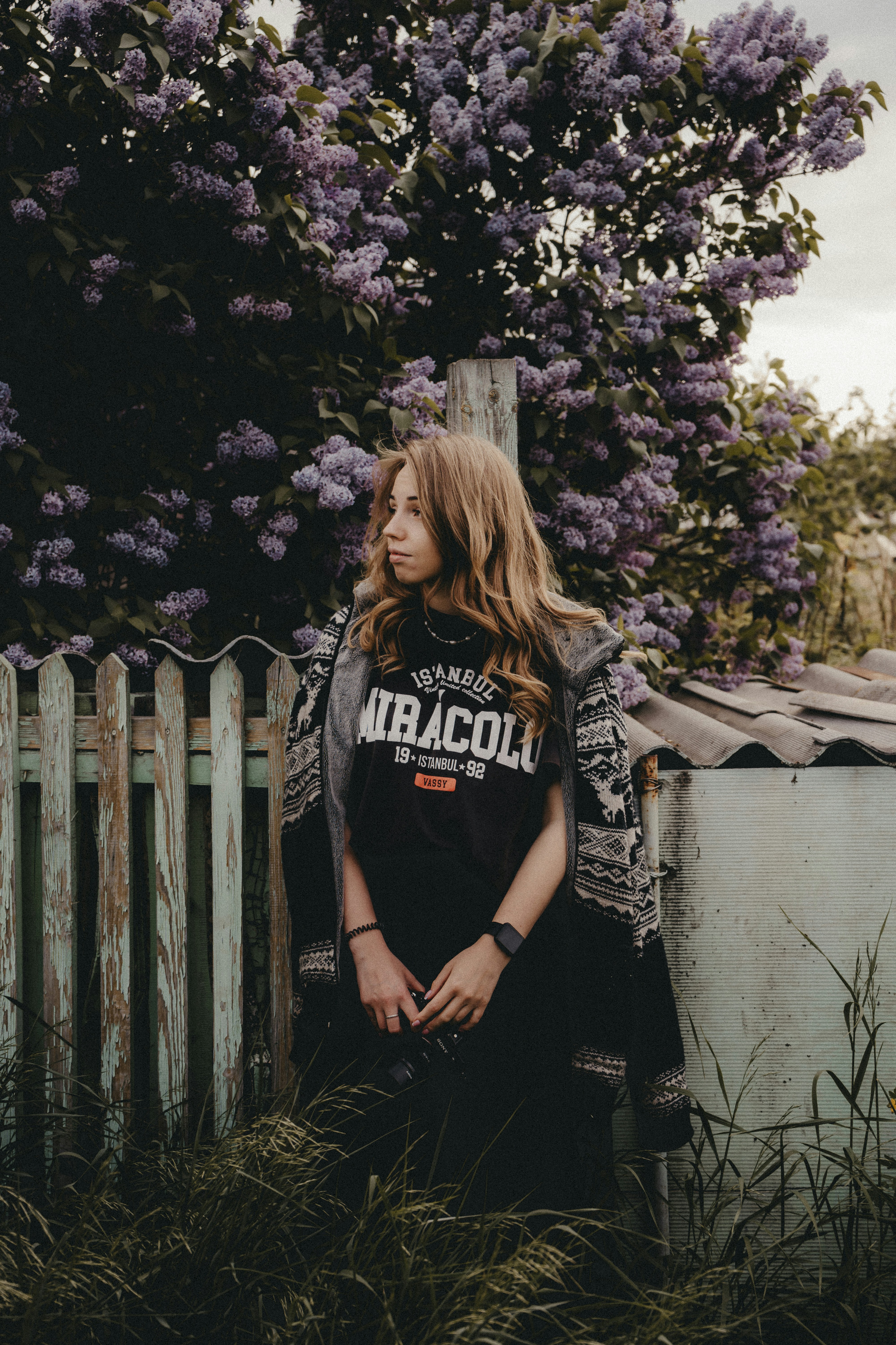 a woman standing next to a wooden fence