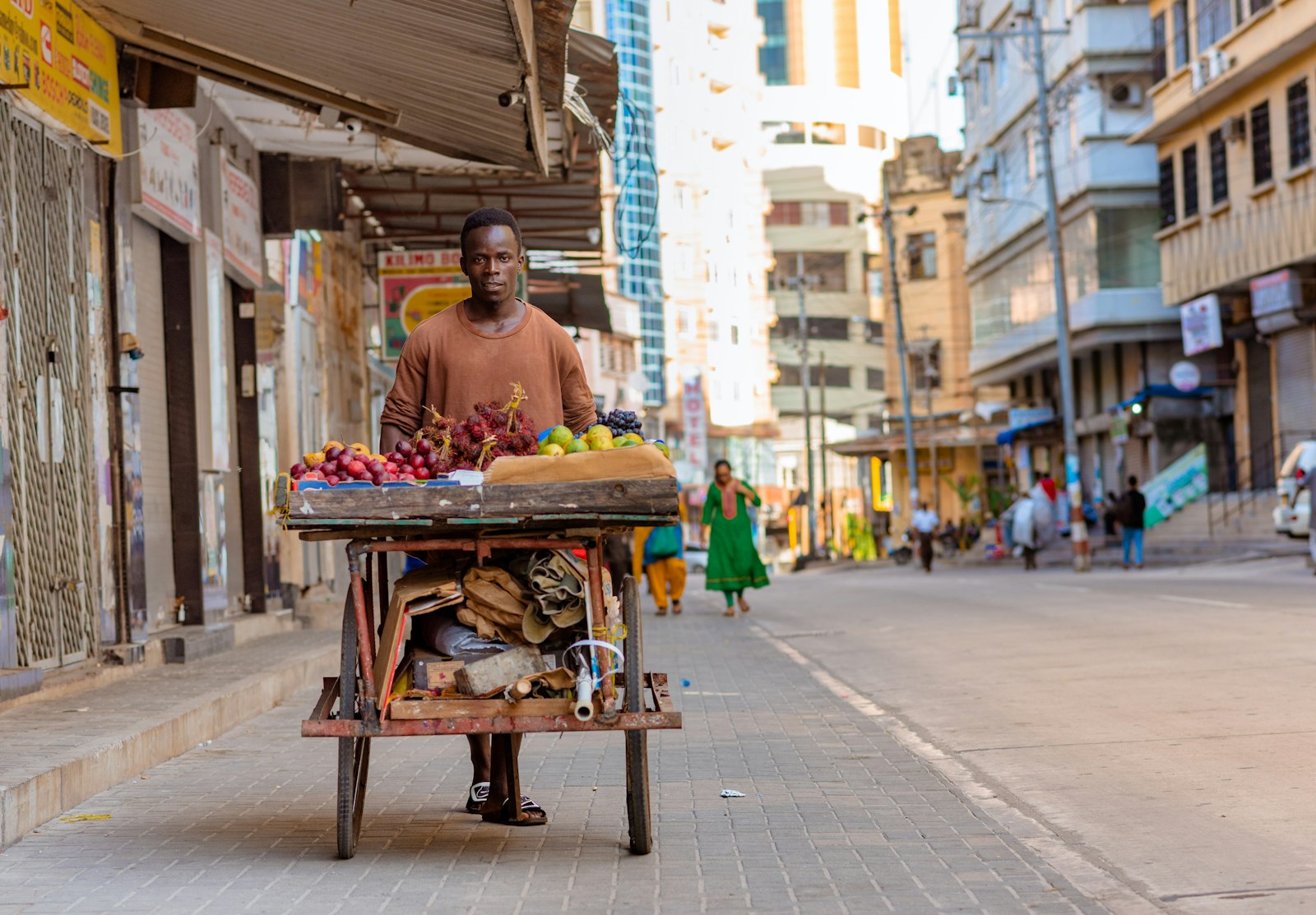 Mchuuzi akisukuma mkokoteni uliojaa matunda katika mtaa wa Dar es Salaam