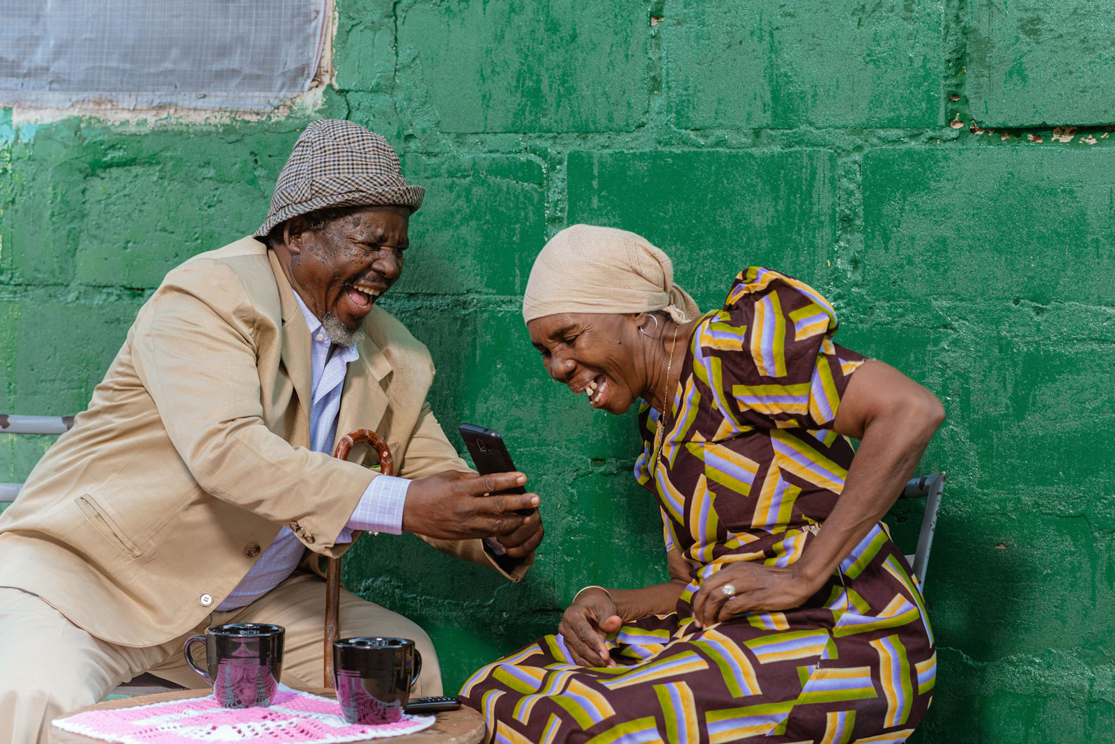Two older adults smiling while using a smartphone in Dar es Salaam