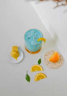 A blue drink with orange slices on a white table