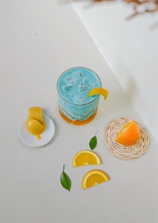 A blue drink with orange slices on a white table